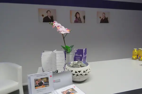 Moderner Empfangsbereich mit Infomaterial, Orchidee und Getränken in einer Tattooentfernungspraxis.