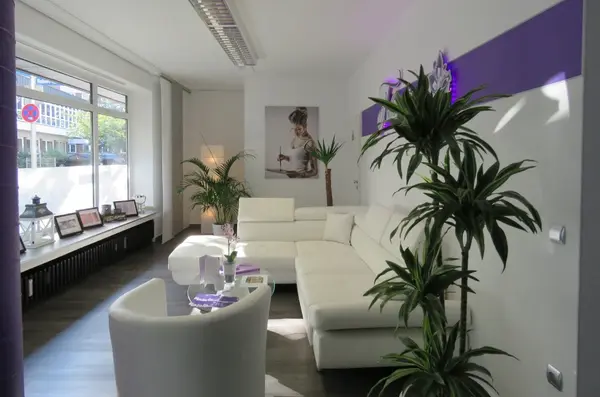 Heller, moderner Wartebereich eines Kosmetikstudios mit weißen Möbeln und Pflanzen.